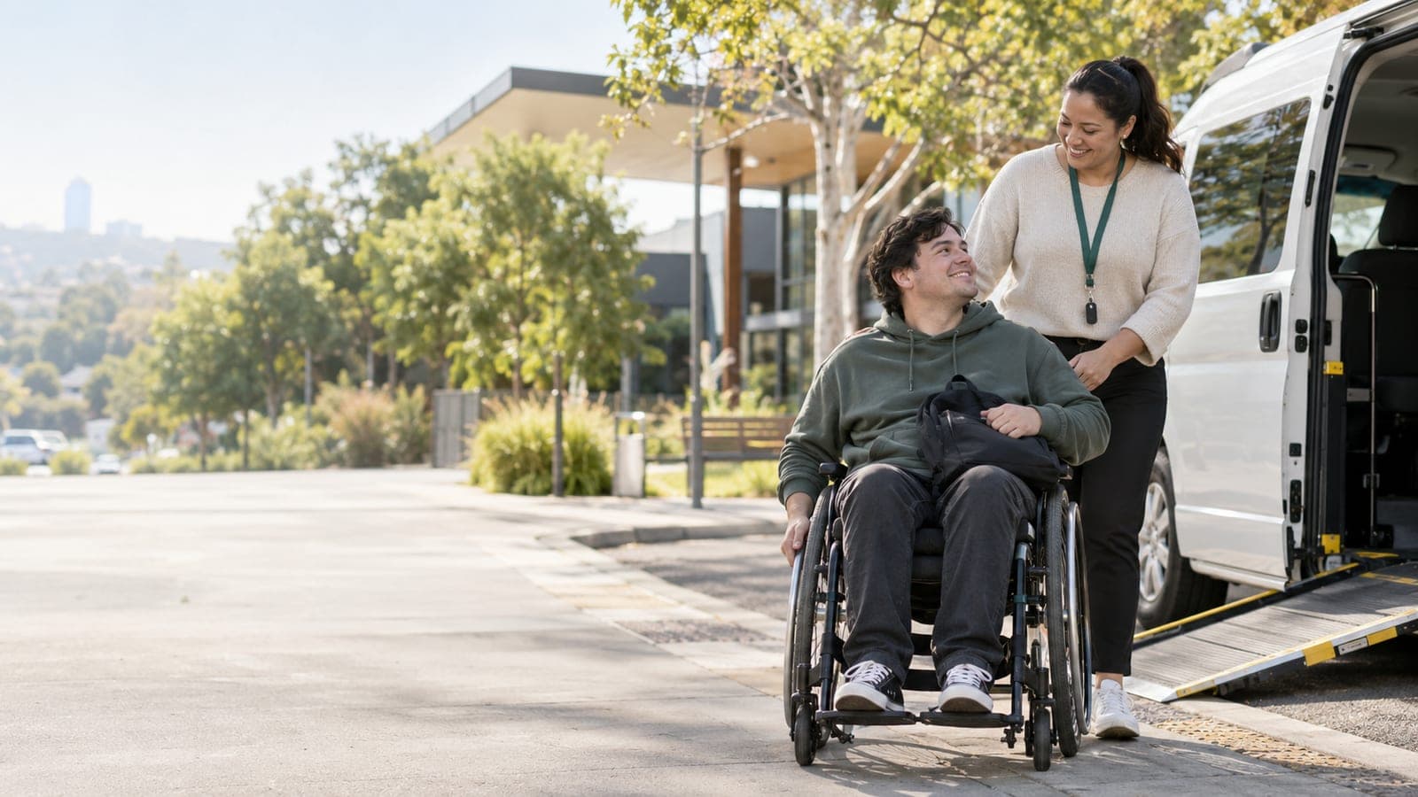 A Valencea support worker walking beside a participant in a wheelchair towards an accessible van with its ramp lowered