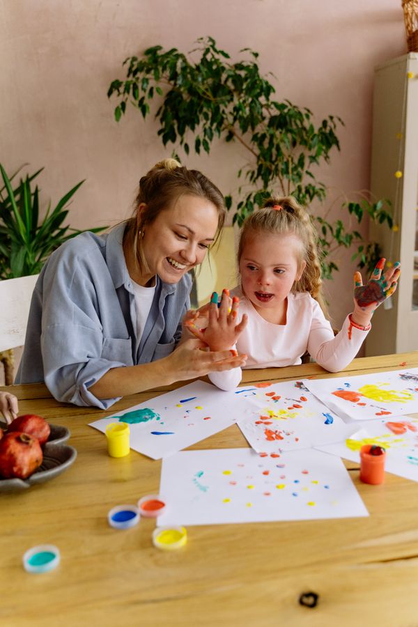 A mother and daughter with Down syndrome finger painting together